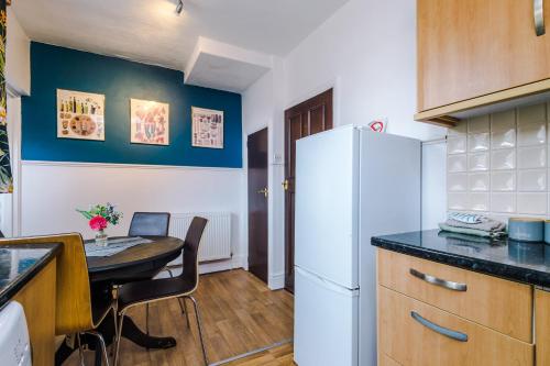 a kitchen with a table and a white refrigerator at Cosy 2 Bedroom house-Short drive from Blackpool Pleasure Beach in Blackpool