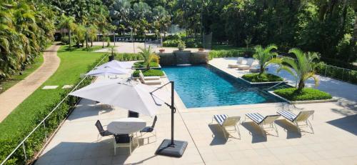 uma piscina com cadeiras e um guarda-sol e uma mesa e cadeiras em Radio Hotel Resort & Convention em Serra Negra