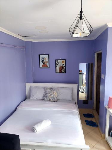- une chambre avec un lit blanc et un mur bleu dans l'établissement Jeda Homey Homes Studio Apartment, à Bomet