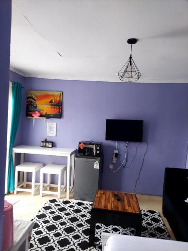 una sala de estar con una pared de color púrpura y una mesa. en Jeda Homey Homes Studio Apartment, en Bomet