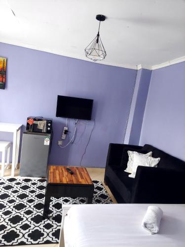 sala de estar con sofá negro y pared azul en Jeda Homey Homes Studio Apartment, en Bomet