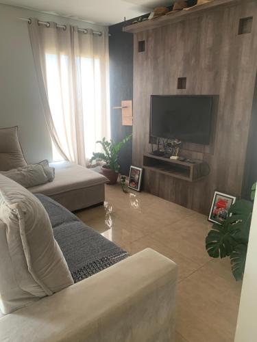 sala de estar con sofá y TV de pantalla plana en Linda Casa Próximo Aeroporto, en Campo Grande