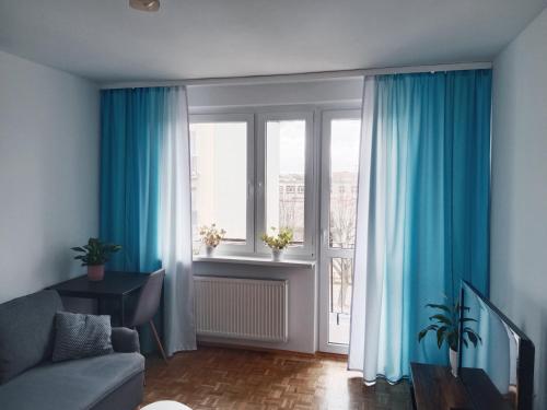 salon z niebieskimi zasłonami, kanapą i oknem w obiekcie Mieszkanie Turkus w Gnieźnie w Gnieźnie