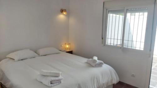 Un dormitorio con una cama blanca con toallas. en Del Parque Flats Picasso Townhouse, en Marbella