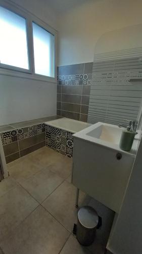 een badkamer met een wastafel, een bad en een raam bij Le Voltaire -2 chambres- 70m2- HYPERCENTRE-Parking-WIFI FIBRE in Tarbes