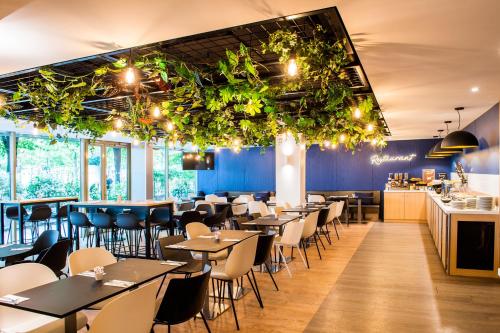 a restaurant with tables and chairs and plants on the ceilings at Holiday Inn Express Paris-Canal De La Villette by IHG in Paris