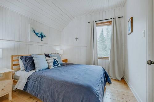 a bedroom with a bed with blue sheets and a window at Chalet - Le Blue Hill in Saint Adolphe D'Howard