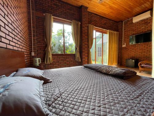a bedroom with a large bed and a brick wall at Mộc House in Kon Tum Kơ Pang