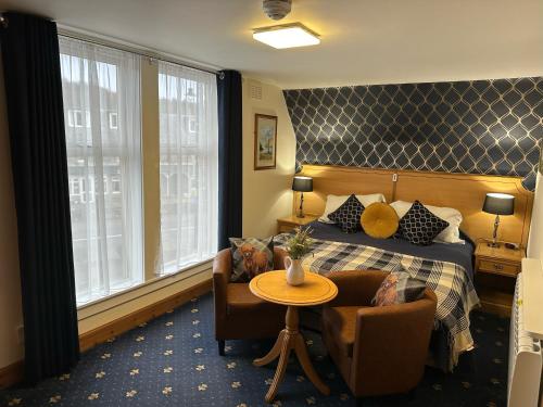 ニュートンモアにあるThe Glen Hotel Newtonmoreのベッド、テーブル、椅子が備わるホテルルームです。