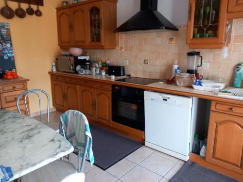 - une cuisine avec des placards en bois et un lave-vaisselle blanc dans l'établissement Chambres a louer pour JO PARIS 2024, à Chèvreville