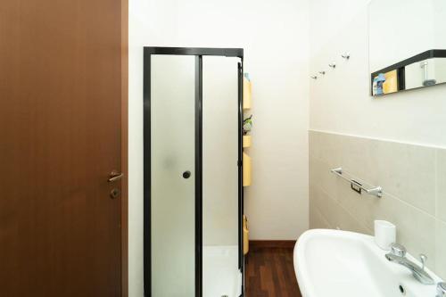 La salle de bains est pourvue d'une porte en verre et d'un lavabo. dans l'établissement Rustico con idromassaggio vista lago, à Brienno