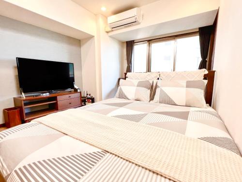 a bedroom with a bed and a flat screen tv at East Ikebukuro 2 Double Beds Apartment / Sunshine City in Tokyo
