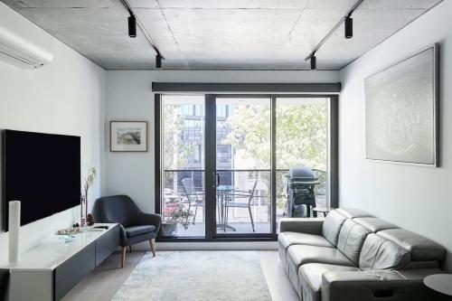 a living room with a couch and a tv at 'Modern Minimalism' Slate Chic in the City in Melbourne