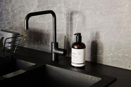 a bottle of wine sitting on a counter next to a sink at 'Modern Minimalism' Slate Chic in the City in Melbourne