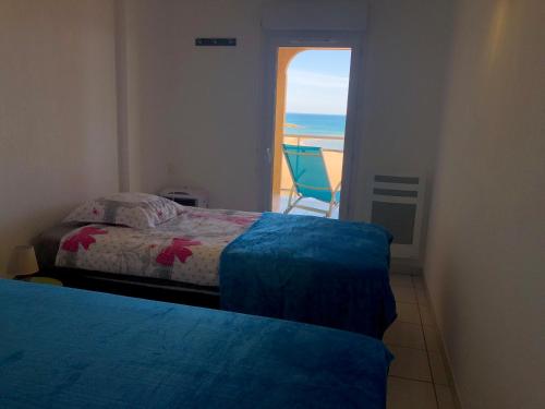 a bedroom with two beds and a view of the ocean at Appartement Front de mer in Valras-Plage