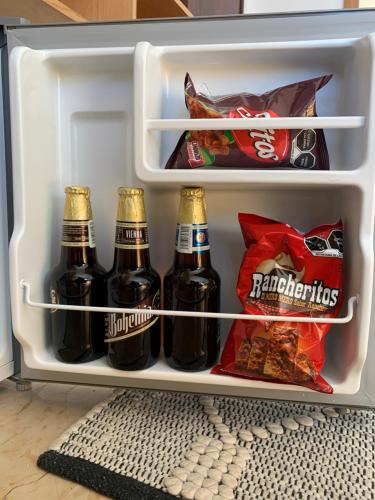a refrigerator filled with bottles of beer and snacks at CHOLULA SUITES in Cholula