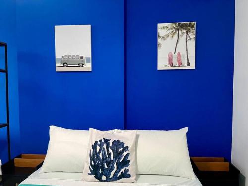 eine blaue Wand mit einem Bett und zwei rosa Stühlen in der Unterkunft Studio Acqua - estilo no melhor bairro da cidade in Niterói