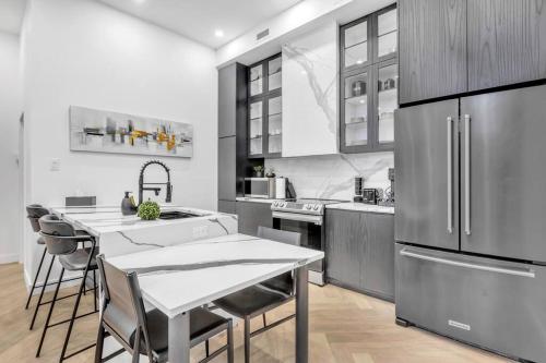 a kitchen with a table and a stainless steel refrigerator at Stylish 2-bedroom Getaway, Luxurious & Conveniently Located to Experience the Pulse of the City - Apt 5 in Montréal