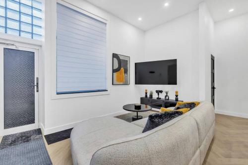 a living room with a couch and a tv at Stylish 2-bedroom Getaway, Luxurious & Conveniently Located to Experience the Pulse of the City - Apt 5 in Montréal