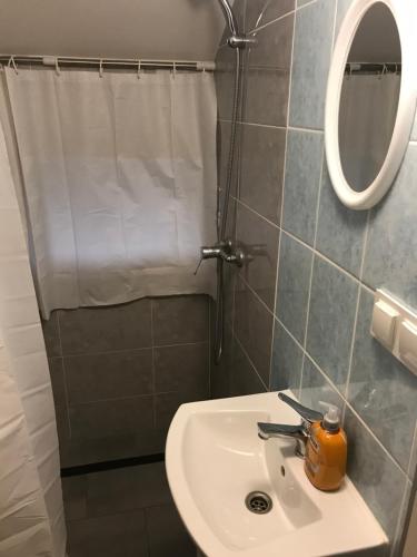 W łazience znajduje się umywalka, lustro i prysznic. w obiekcie Kris Pokoje w mieście Kajetany