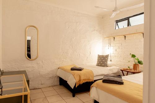 een slaapkamer met 2 bedden en een spiegel bij Hartland Huis in Graaff-Reinet