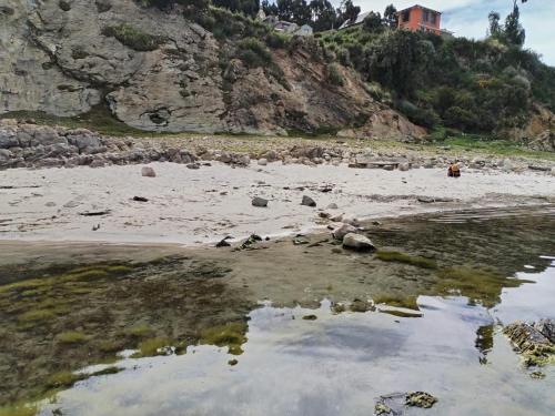 a beach with rocks and water and a mountain at ECO CABAÑA INTIWAT'A in Comunidad Challapampa