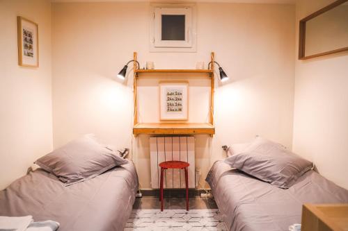 Cette chambre comprend deux lits, une table et un tabouret. dans l'établissement Charming souplex in Paris, à Paris
