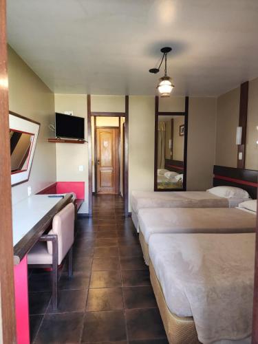 a hotel room with four beds and a desk at Baia Cabralia Hotel in Santa Cruz Cabrália