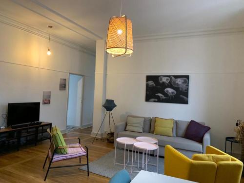 a living room with a couch and chairs and a tv at MARTROI Cœur de Ville in Orléans