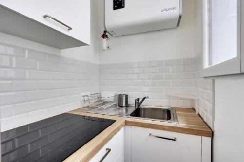 une cuisine avec des armoires blanches et un évier dans l'établissement studio cosy jules Joffrin, à Paris