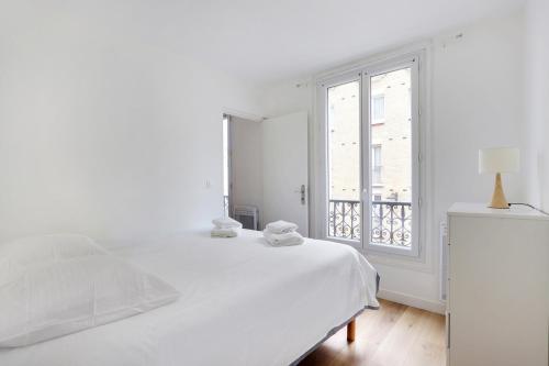une chambre blanche avec un lit et une fenêtre dans l'établissement studio cosy jules Joffrin, à Paris