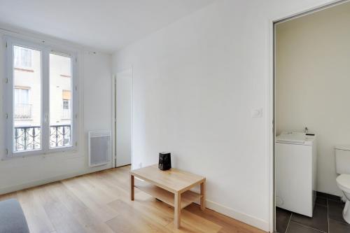 Cette chambre blanche dispose d'une table et d'une fenêtre. dans l'établissement studio cosy jules Joffrin, à Paris