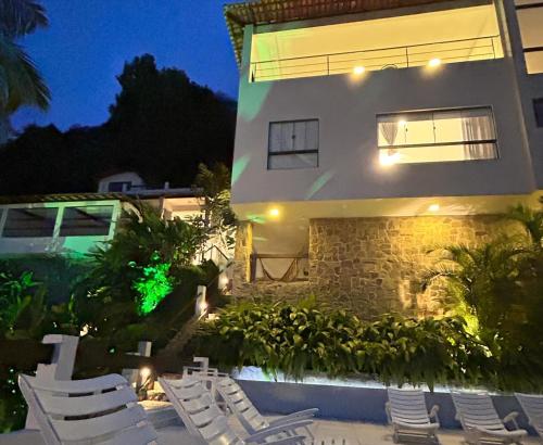 a building with lounge chairs in front of it at night at Oásis Beach House in Angra dos Reis