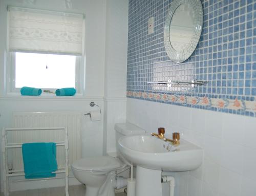 a bathroom with a sink and a toilet and a mirror at Tywyn Beach House in Tywyn