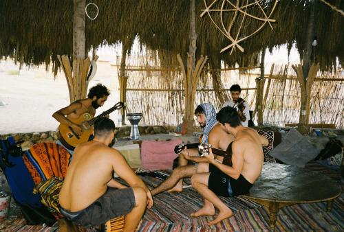 a group of men sitting on the beach playing music at Makany Makanak Camp in Dahab