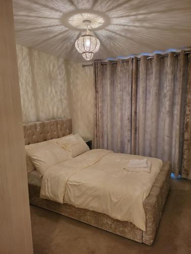 a bedroom with a large bed with a chandelier at Alderhouseplace in Maidenhead