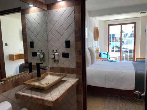 ein Badezimmer mit einem Waschbecken neben einem Bett in der Unterkunft CHOLULA SUITES in Cholula de Rivadavia