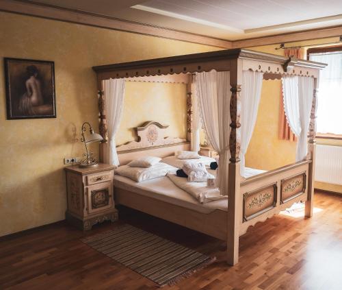 Hétkúti Wellness Hotel في مور: غرفة نوم بسرير مظلة وموقف ليلي