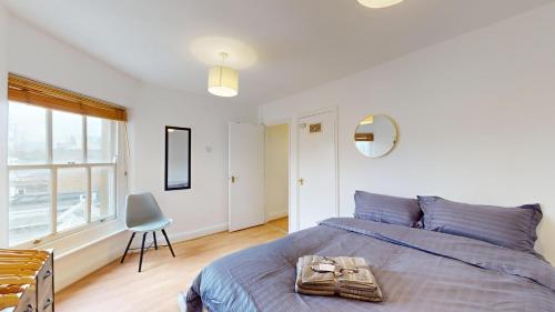 a bedroom with a bed and a chair and a window at My Lovely Clapham Flat in London