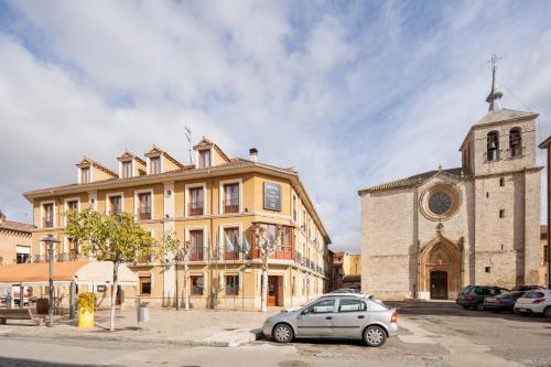 um carro estacionado em frente a um edifício com uma igreja em Hotel Alda Ciudad de Toro em Toro