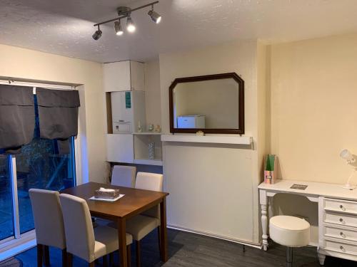 een eetkamer met een tafel en een spiegel bij Contractor & Family Friendly House Romford in Havering atte Bower
