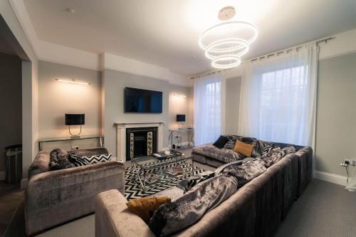 a living room with a large couch and a fireplace at 3 The Steyne - Stunning 5 Storey Georgian house with cinema room in Worthing