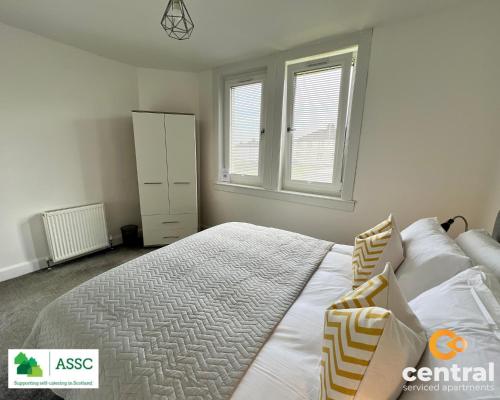 a bedroom with a large bed and two windows at 2 Bedroom Apartment by Central Serviced Apartments - Perfect for Short&Long Term Stays - Family Neighbourhood - Wi-Fi - FREE Street Parking - Sleeps 4 - 2 x King Beds - Smart TV in All Rooms - Modern - Weekly-Monthly Offers - Trade Stays - Close to A90 in Dundee