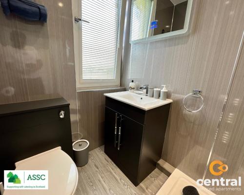 a bathroom with a sink and a toilet and a window at 2 Bedroom Apartment by Central Serviced Apartments - Perfect for Short&Long Term Stays - Family Neighbourhood - Wi-Fi - FREE Street Parking - Sleeps 4 - 2 x King Beds - Smart TV in All Rooms - Modern - Weekly-Monthly Offers - Trade Stays - Close to A90 in Dundee