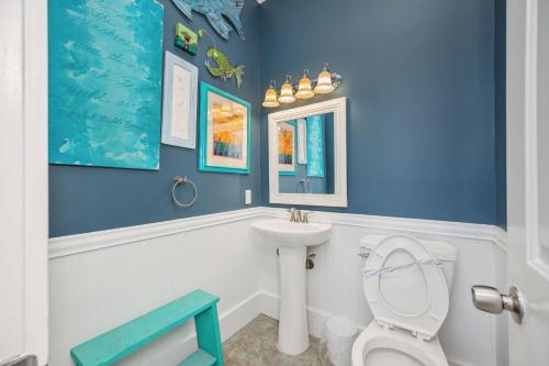 a blue bathroom with a toilet and a sink at Fairwinds by Oak Island Accommodations in Caswell Beach