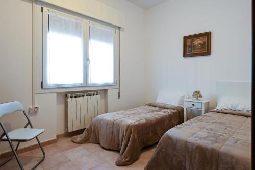 1 Schlafzimmer mit 2 Betten, einem Stuhl und einem Fenster in der Unterkunft Venice Green Lagoon - 20 min da Venezia in Mestre
