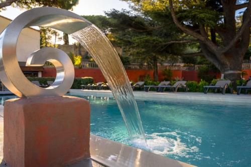 uma fonte de água em frente a uma piscina em Les Jardins Du Cèdre em Port-Vendres