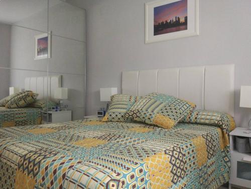 a bedroom with a large bed with a colorful comforter at Céntrico Apartamento Santa Justa in Seville