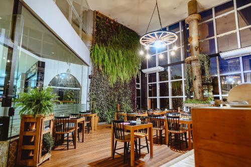 um restaurante com cadeiras e mesas de madeira e janelas em Riellis Center Hotel em Botucatu