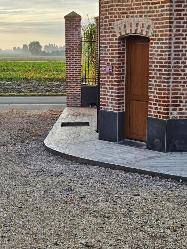 un bâtiment en briques avec une porte sur son côté dans l'établissement Gite canard, à Fromelles